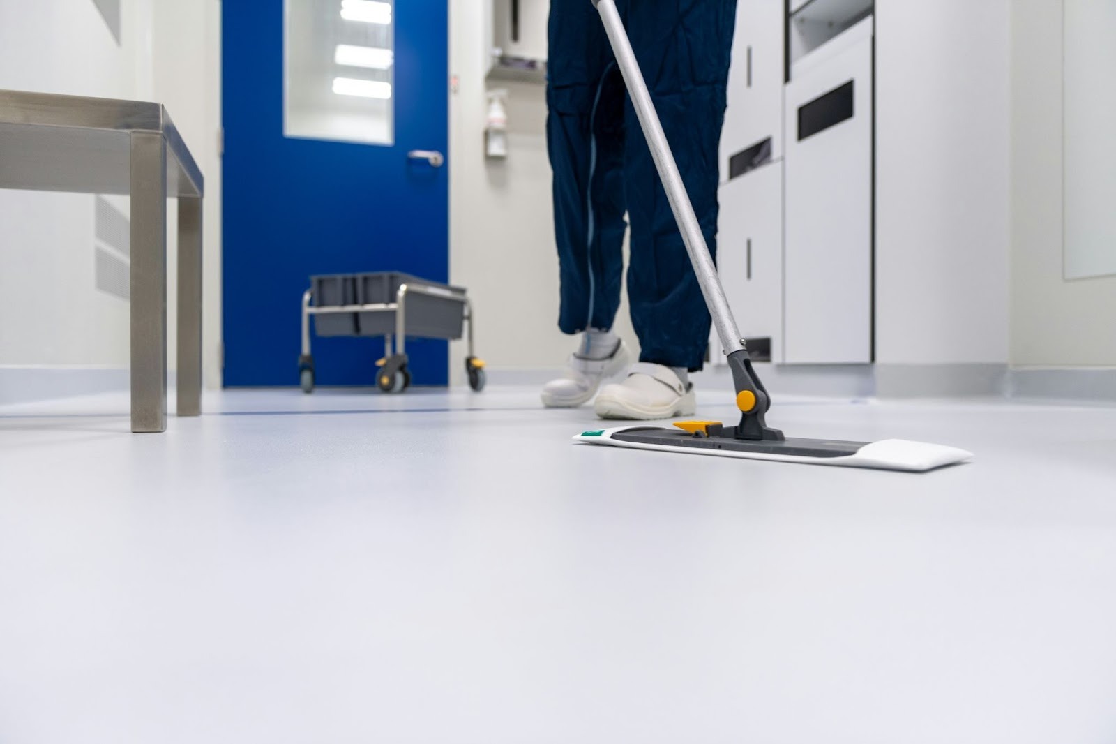 person using a swiffer to clean the floor of a hospital 